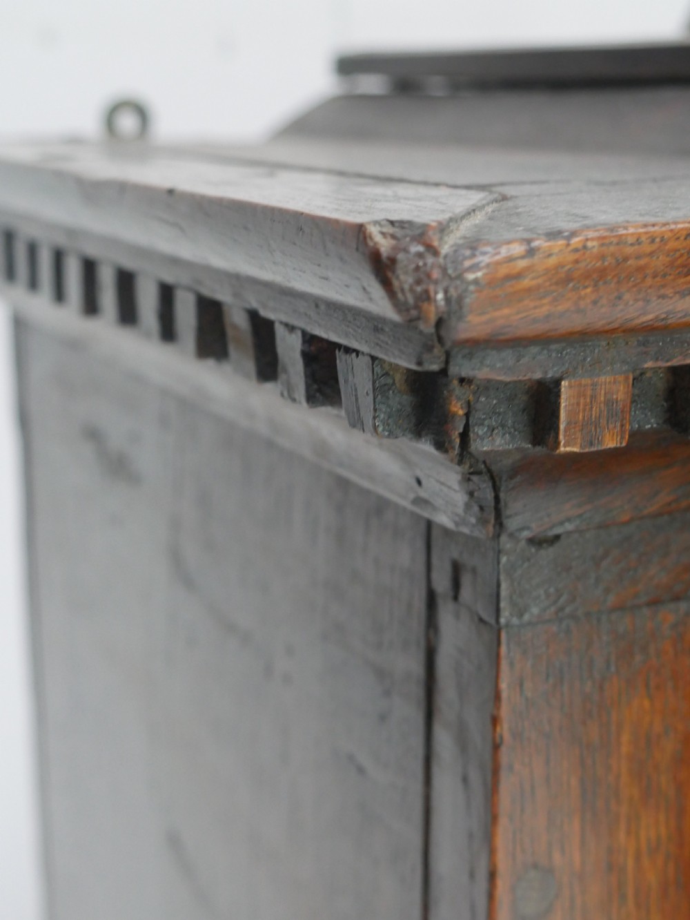 An 18th-century dark oak hanging cupboard featuring a carved shell cresting, a single fielded panel door with brass key escutcheon, and two small base drawers. View XIII