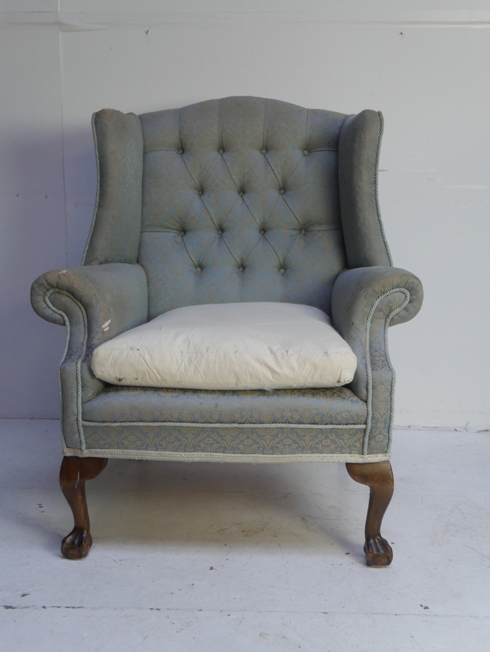 A high-backed wing armchair upholstered in patterned blue damask fabric with a deep buttoned backrest and carved wood cabriole front legs. View II