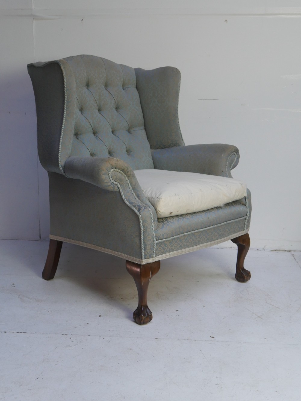 A high-backed wing armchair upholstered in patterned blue damask fabric with a deep buttoned backrest and carved wood cabriole front legs. View VIII