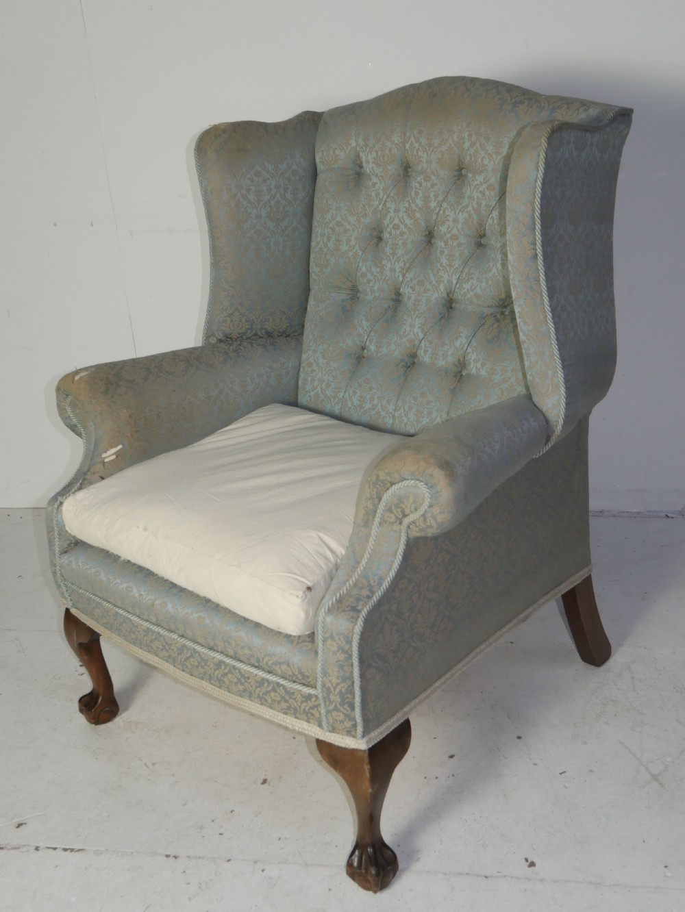 A high-backed wing armchair upholstered in patterned blue damask fabric with a deep buttoned backrest and carved wood cabriole front legs. View XIII