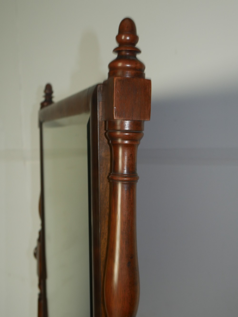 A Regency mahogany cheval mirror featuring turned side supports, finials, adjustable side knobs, and splayed legs on brass castors. View III
