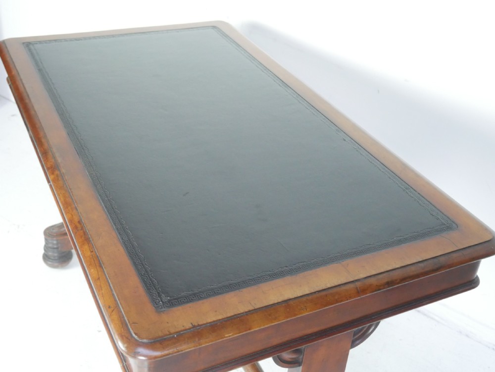 A mahogany writing desk featuring a dark leather inset top, two frieze drawers, and a turned stretcher connecting carved trestle end supports. View II
