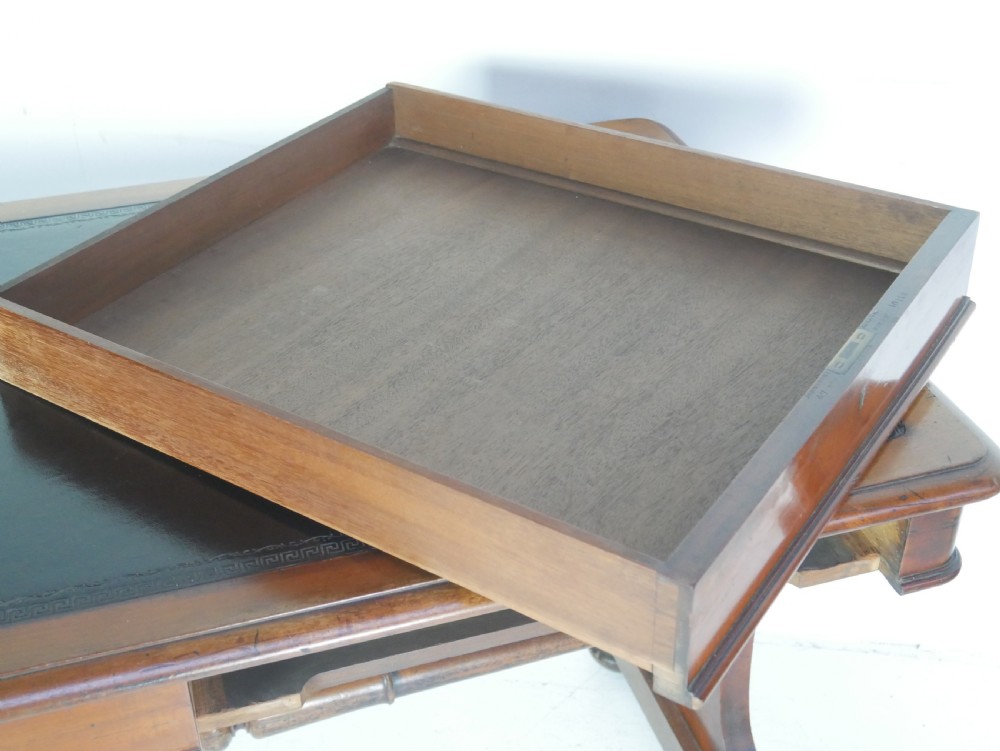 A mahogany writing desk featuring a dark leather inset top, two frieze drawers, and a turned stretcher connecting carved trestle end supports. View VI