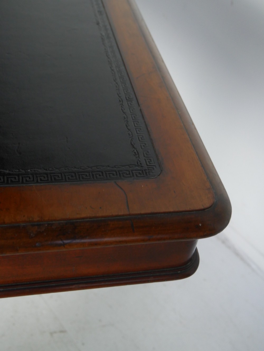 A mahogany writing desk featuring a dark leather inset top, two frieze drawers, and a turned stretcher connecting carved trestle end supports. View IX