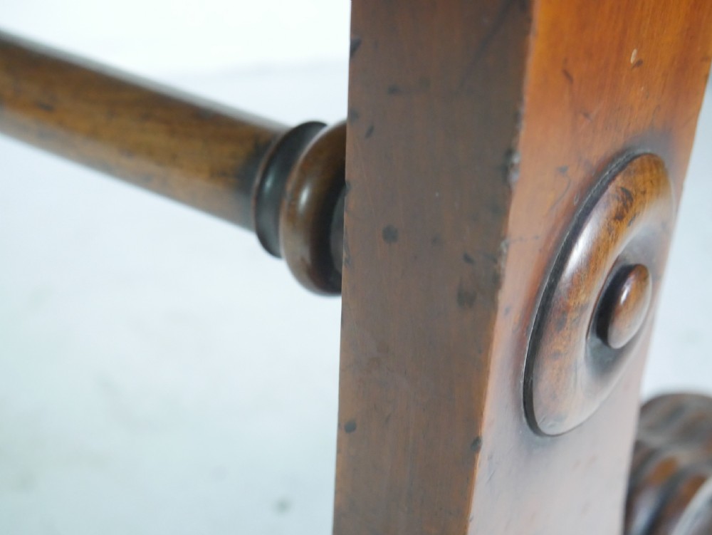 A mahogany writing desk featuring a dark leather inset top, two frieze drawers, and a turned stretcher connecting carved trestle end supports. View XI