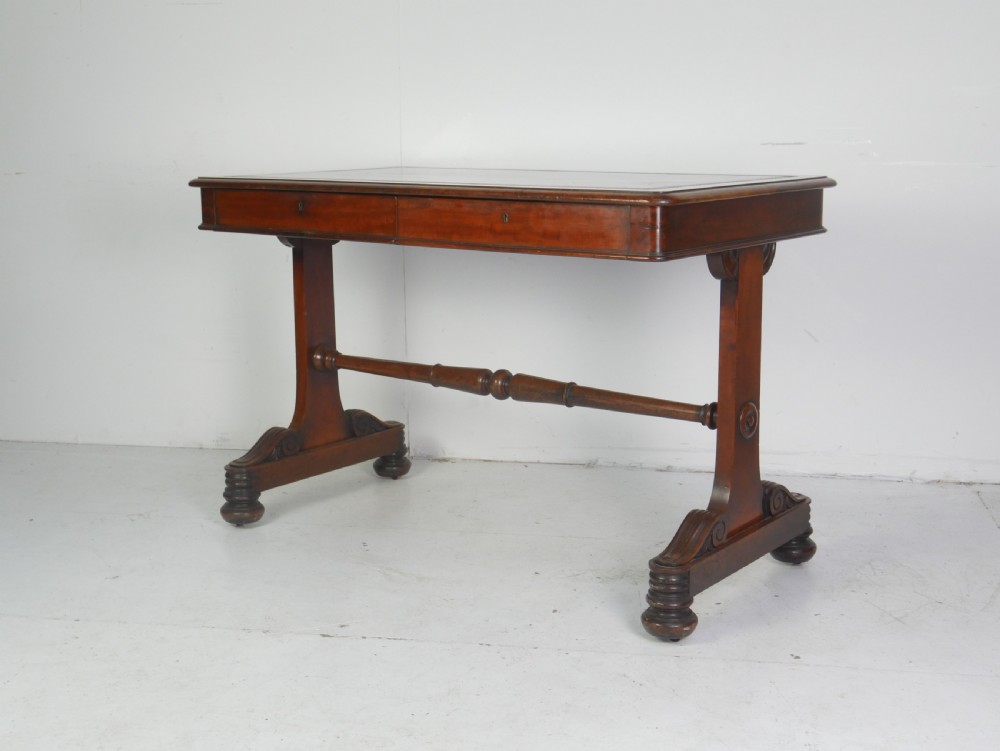 A mahogany writing desk featuring a dark leather inset top, two frieze drawers, and a turned stretcher connecting carved trestle end supports. View XIII