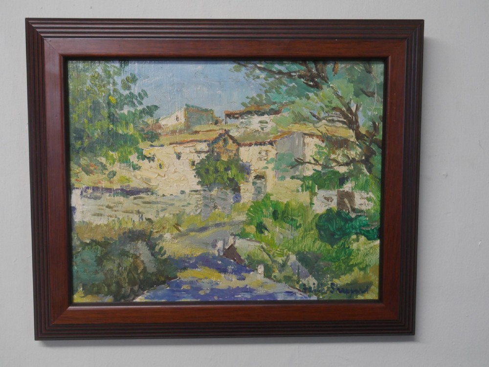 An impressionist oil painting depicting a sunny French village landscape with stone buildings and trees, presented in a dark wooden frame. View IV