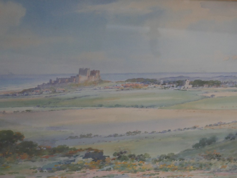 A framed watercolour landscape painting by Frank Wood depicting Bamburgh Castle on the Northumberland coast under a pale sky. View III