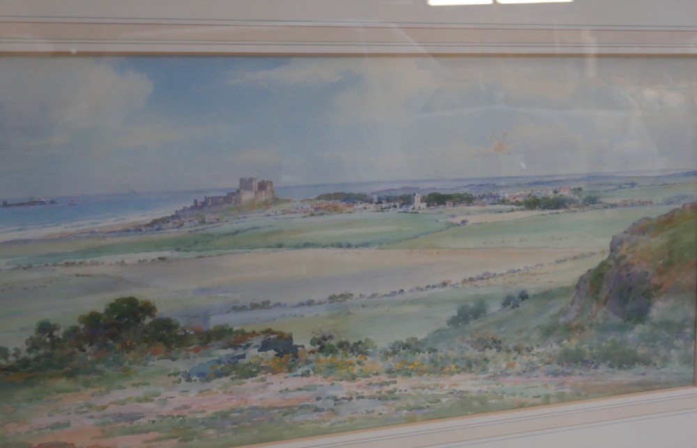 A framed watercolour landscape painting by Frank Wood depicting Bamburgh Castle on the Northumberland coast under a pale sky. View IV