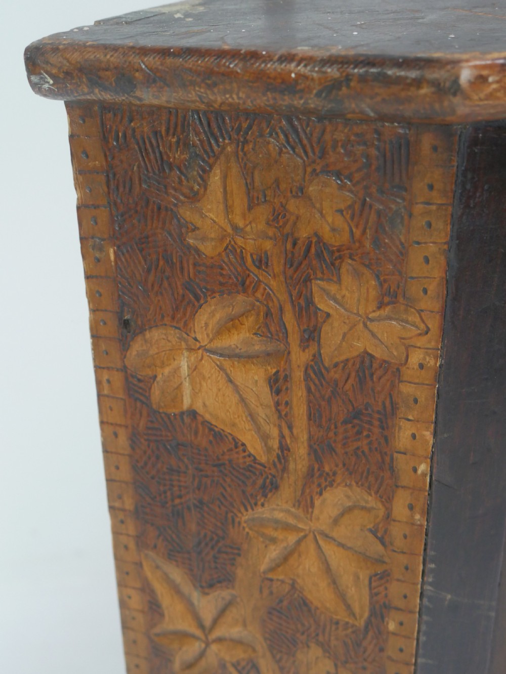 A dark carved wood wall-hanging corner cabinet featuring relief-carved ivy leaves on the side panels, a single glass door, a brass catch, and a red interior. View II