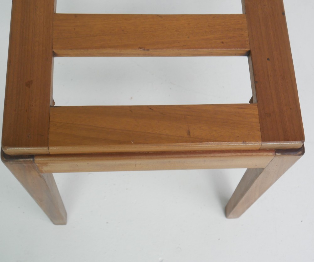 A warm brown wooden luggage rack featuring a slatted rectangular top resting on four square tapered legs. View VII