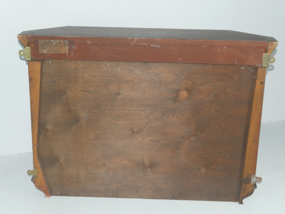 A wall-mounted mahogany display cabinet featuring glazed doors, canted side panels, decorative wood marquetry on the upper frieze, and a brass key escutcheon. View XII