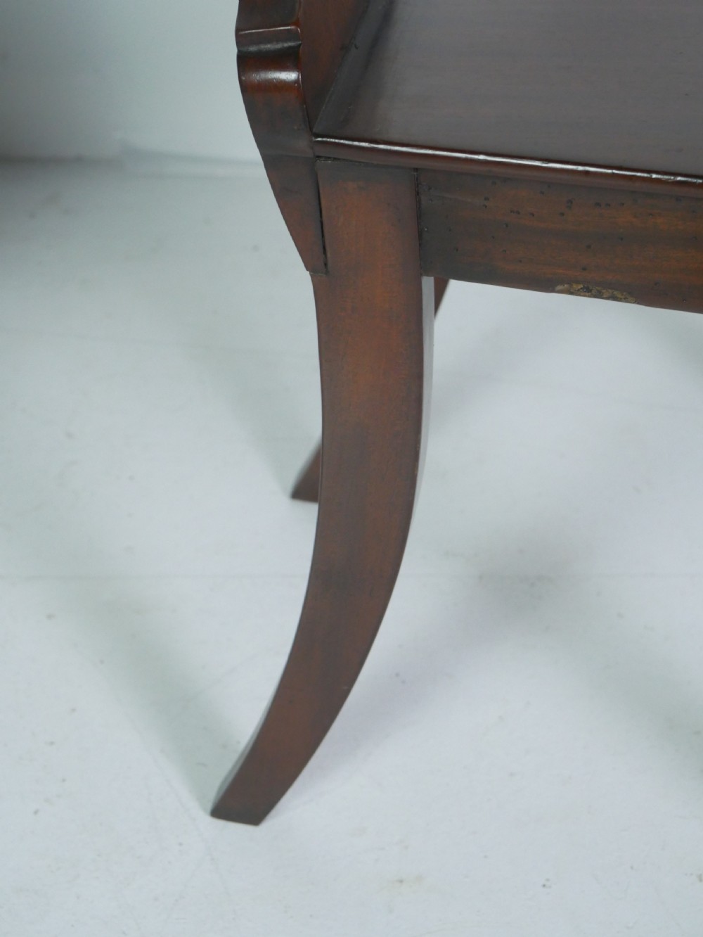 A pair of antique Regency mahogany hall chairs featuring octagonal carved backs with central shield motifs, solid timber seats, and turned front legs. View X