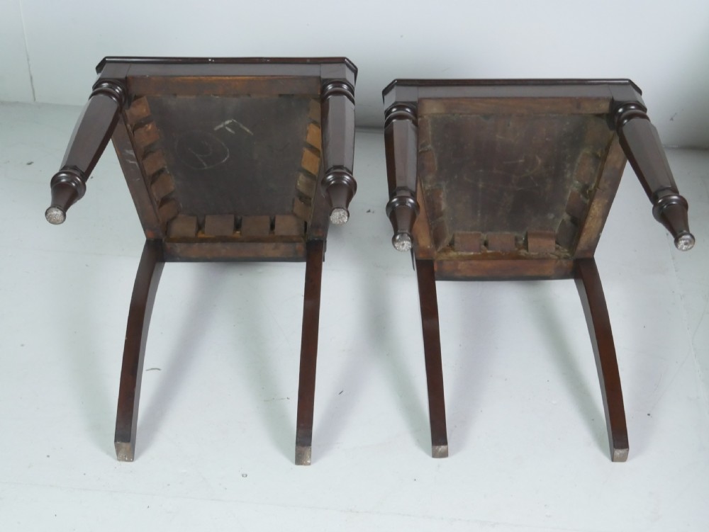 A pair of antique Regency mahogany hall chairs featuring octagonal carved backs with central shield motifs, solid timber seats, and turned front legs. View XI