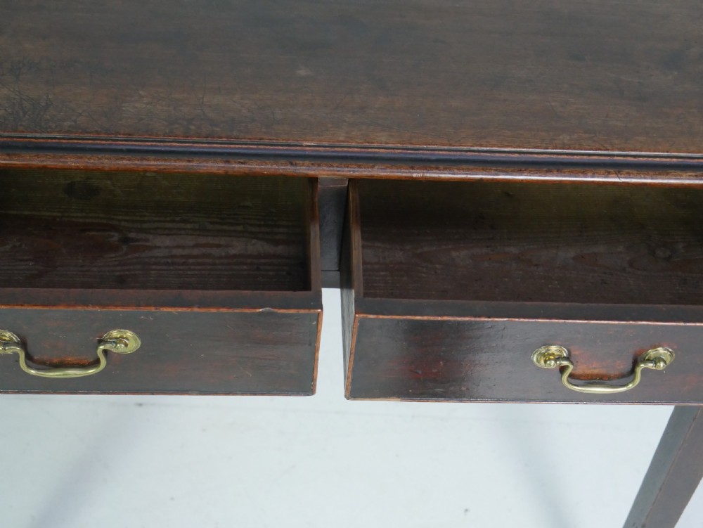 A dark mahogany Georgian side table featuring two front drawers with brass swan-neck handles and square tapered legs. View VII