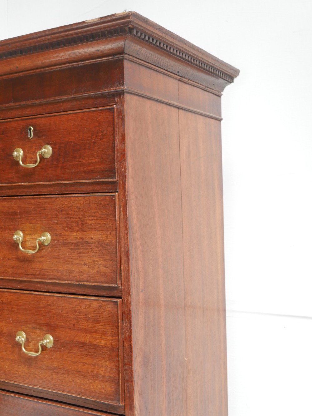 A tall Georgian oak chest on chest featuring brass swan-neck handles, keyhole escutcheons, and bracket feet. View V