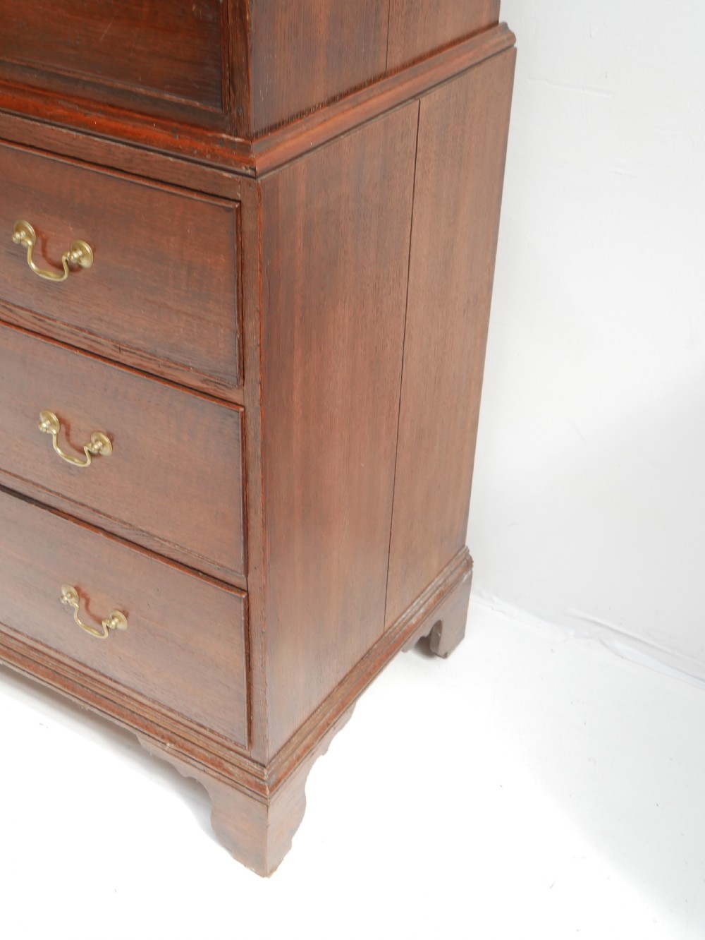 A tall Georgian oak chest on chest featuring brass swan-neck handles, keyhole escutcheons, and bracket feet. View VI