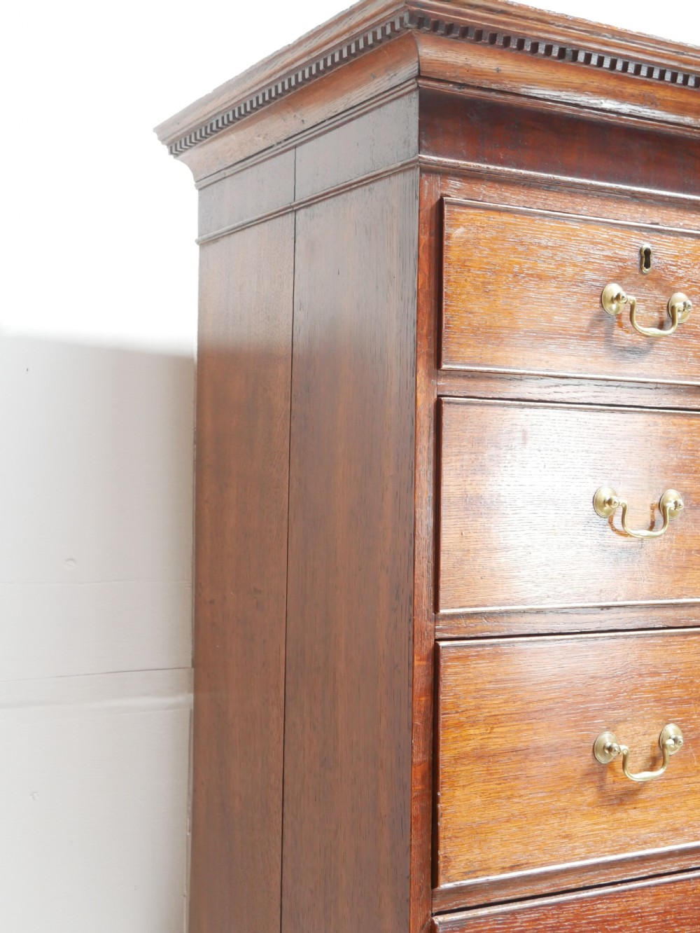 A tall Georgian oak chest on chest featuring brass swan-neck handles, keyhole escutcheons, and bracket feet. View VII