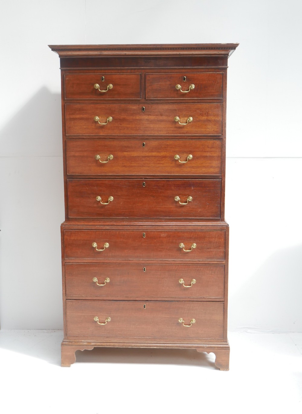 A tall Georgian oak chest on chest featuring brass swan-neck handles, keyhole escutcheons, and bracket feet. View XI