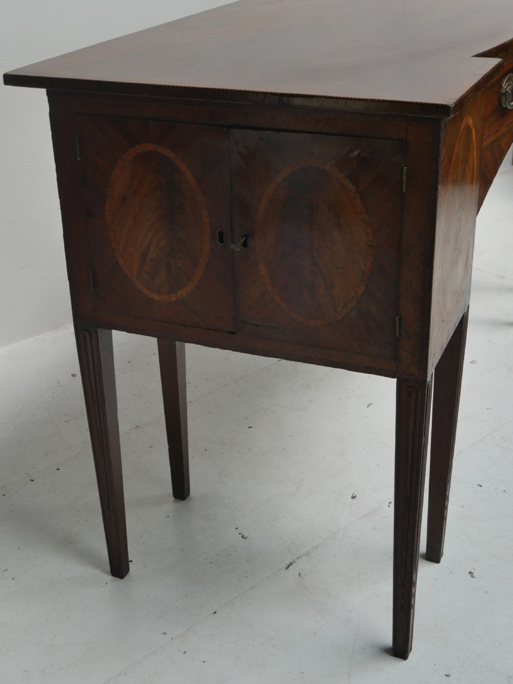 A Georgian mahogany sideboard featuring marquetry fan inlays, oval veneer door panels, a central drawer, and square tapered legs. View VIII