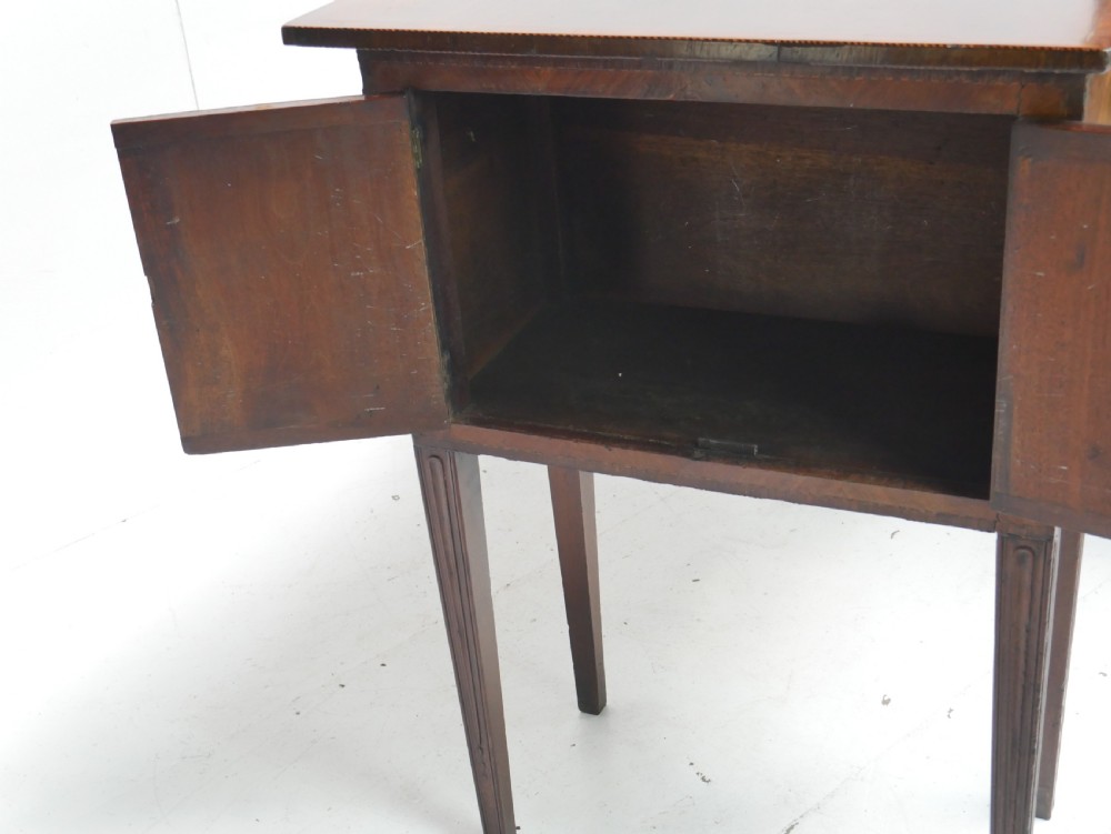 A Georgian mahogany sideboard featuring marquetry fan inlays, oval veneer door panels, a central drawer, and square tapered legs. View X