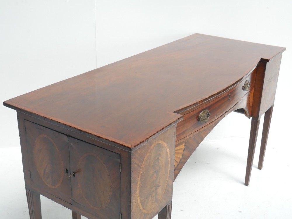 A Georgian mahogany sideboard featuring marquetry fan inlays, oval veneer door panels, a central drawer, and square tapered legs. View XII
