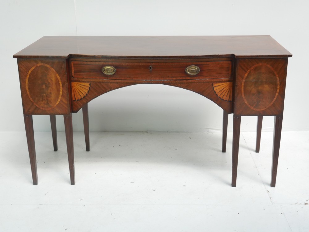 A Georgian mahogany sideboard featuring marquetry fan inlays, oval veneer door panels, a central drawer, and square tapered legs. View XX