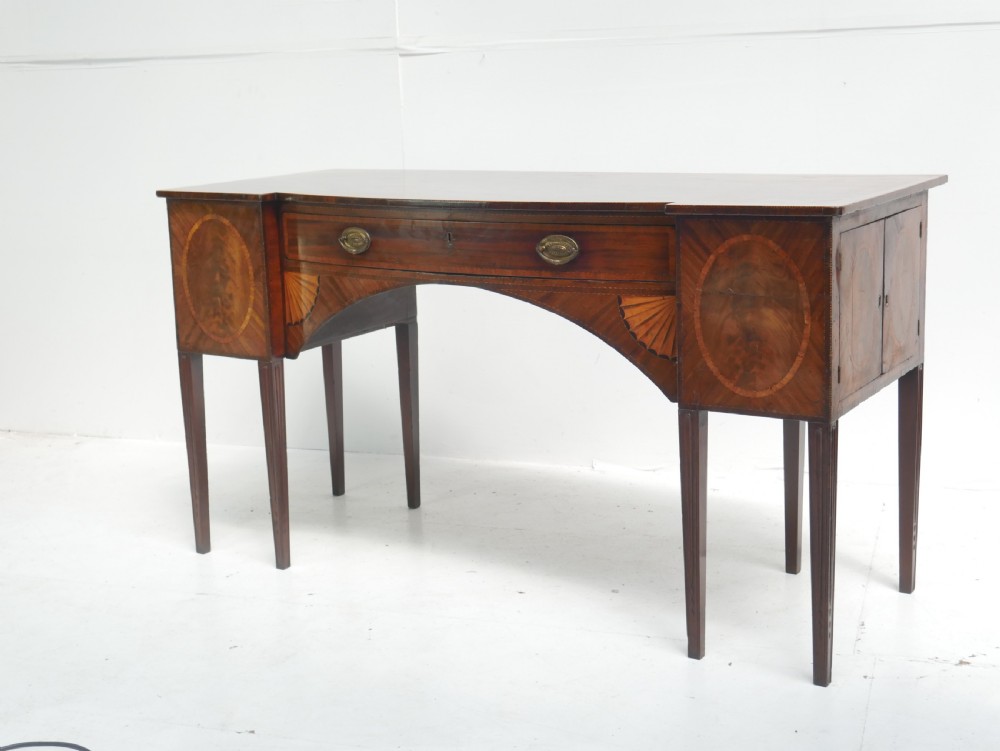 A Georgian mahogany sideboard featuring marquetry fan inlays, oval veneer door panels, a central drawer, and square tapered legs. View XXI