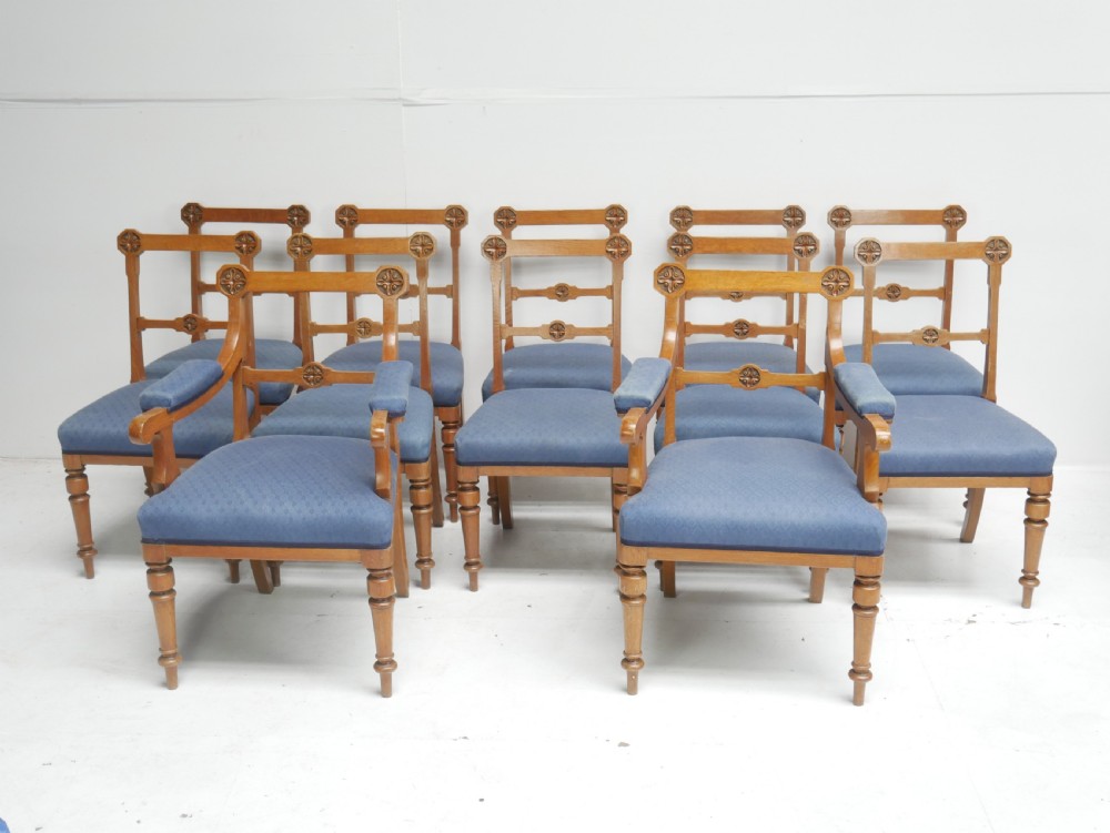 A set of twelve carved oak dining chairs with blue fabric upholstered seats and turned front legs.