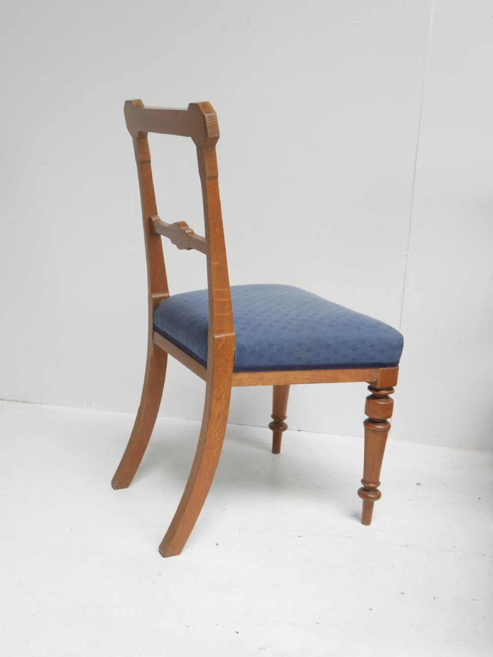 A set of twelve carved oak dining chairs with blue fabric upholstered seats and turned front legs. View II
