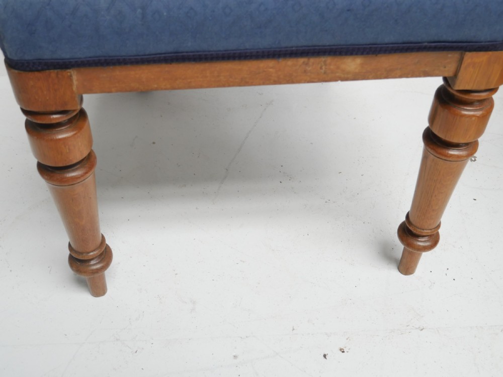 A set of twelve carved oak dining chairs with blue fabric upholstered seats and turned front legs. View III