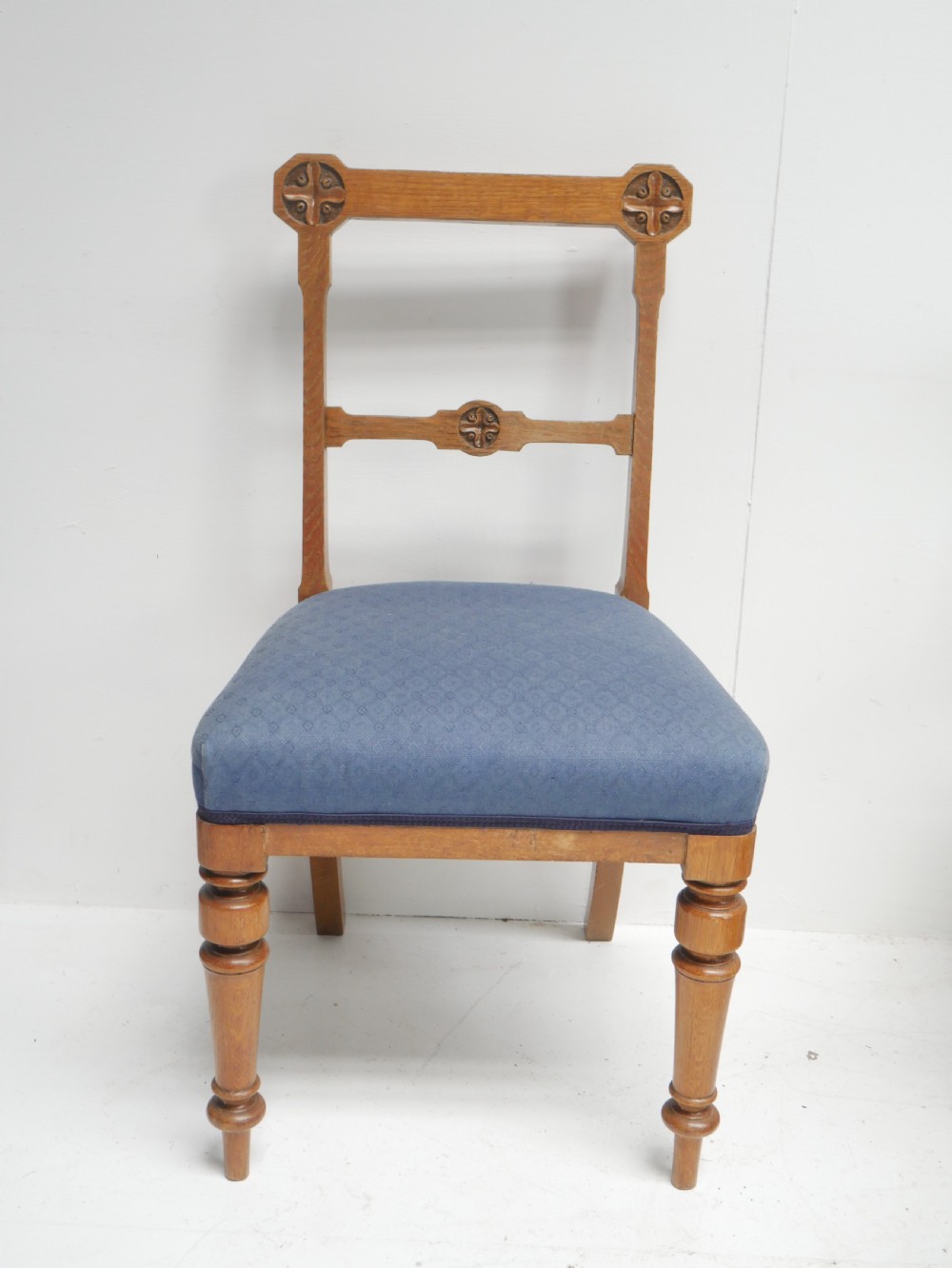 A set of twelve carved oak dining chairs with blue fabric upholstered seats and turned front legs. View VI
