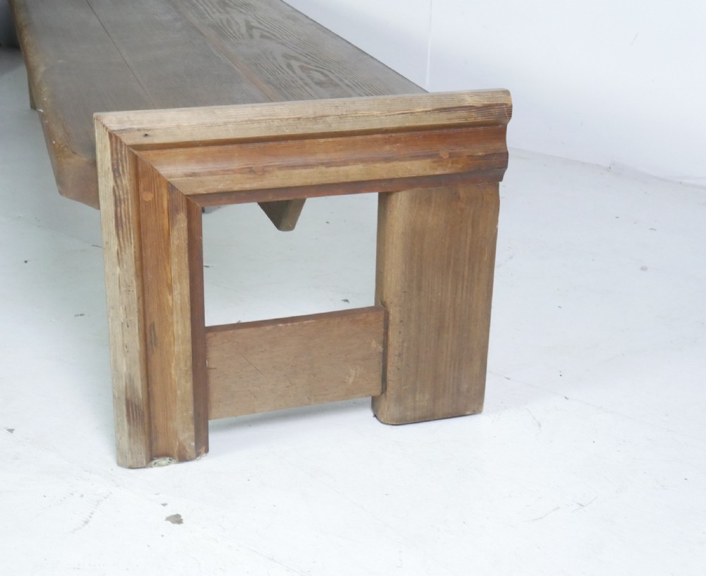 A long, rustic solid pine bench featuring raised side panels and sturdy central support legs. View V