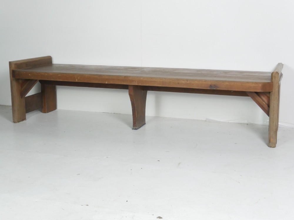 A long, rustic solid pine bench featuring raised side panels and sturdy central support legs. View IX