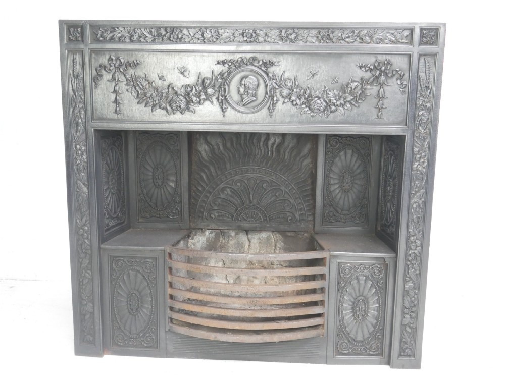 A dark cast iron register grate decorated with carved floral swags, a central profile medallion, and a fan-motif back plate above a curved front grate. View II