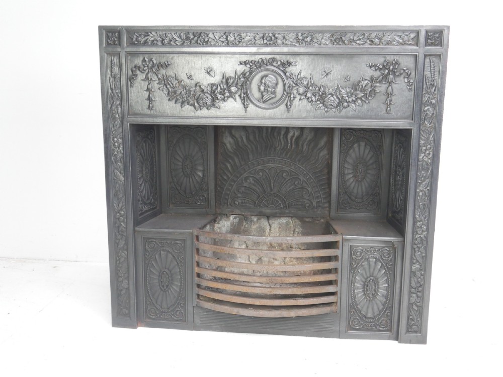 A dark cast iron register grate decorated with carved floral swags, a central profile medallion, and a fan-motif back plate above a curved front grate. View III