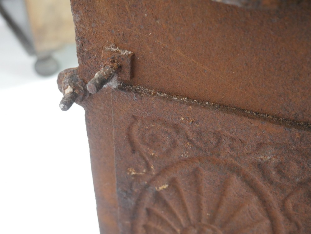 A dark cast iron register grate decorated with carved floral swags, a central profile medallion, and a fan-motif back plate above a curved front grate. View XIII