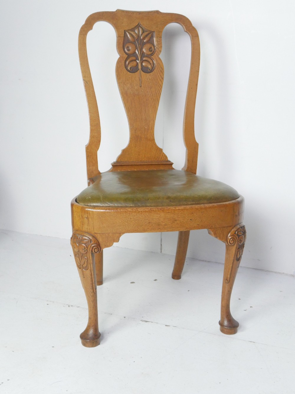 A large set of fourteen carved oak dining chairs featuring shaped back splats, drop-in upholstered seats, and cabriole front legs. View III