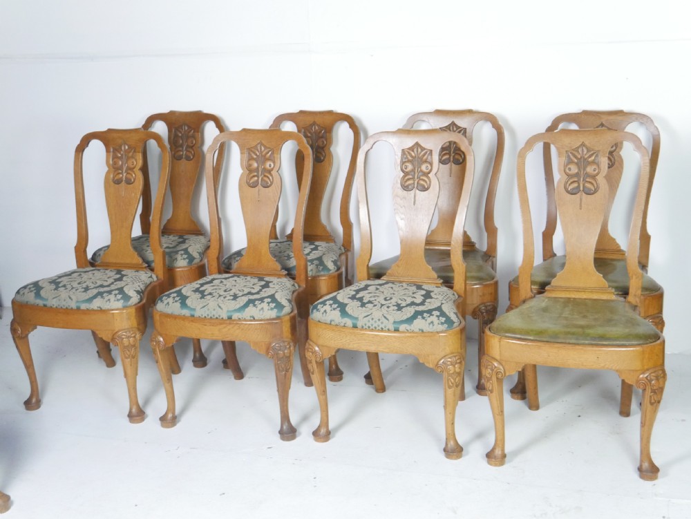 A large set of fourteen carved oak dining chairs featuring shaped back splats, drop-in upholstered seats, and cabriole front legs. View XI