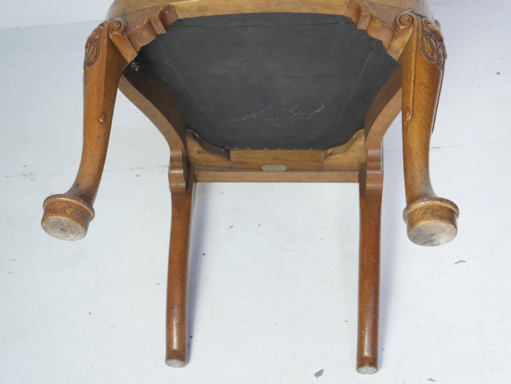 A large set of fourteen carved oak dining chairs featuring shaped back splats, drop-in upholstered seats, and cabriole front legs. View XXII