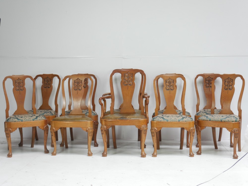 A large set of fourteen carved oak dining chairs featuring shaped back splats, drop-in upholstered seats, and cabriole front legs. View XV