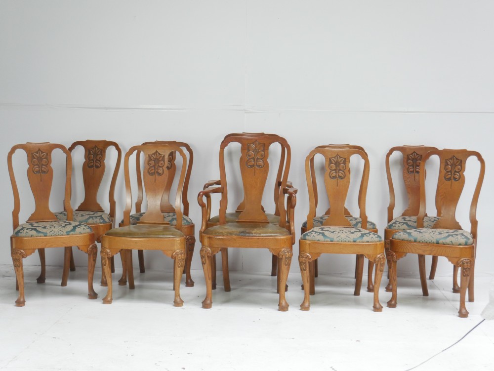 A large set of fourteen carved oak dining chairs featuring shaped back splats, drop-in upholstered seats, and cabriole front legs. View XVI