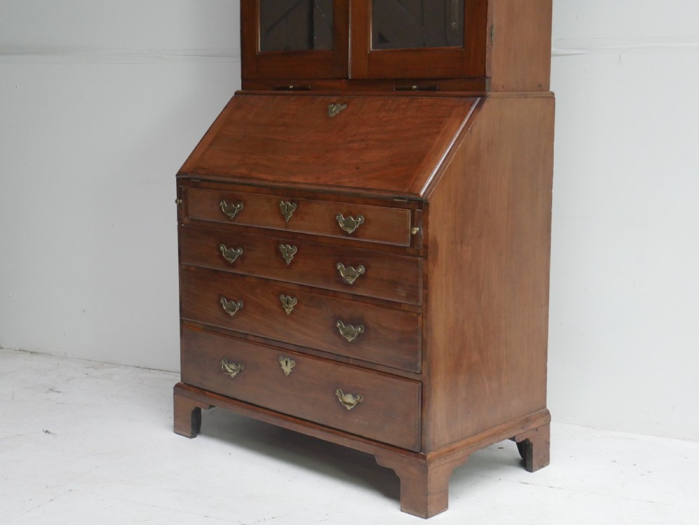 A tall Georgian mahogany bureau bookcase featuring a swan-neck pediment, glazed upper doors, a slant-front writing slope, four long drawers, and bracket feet. View II