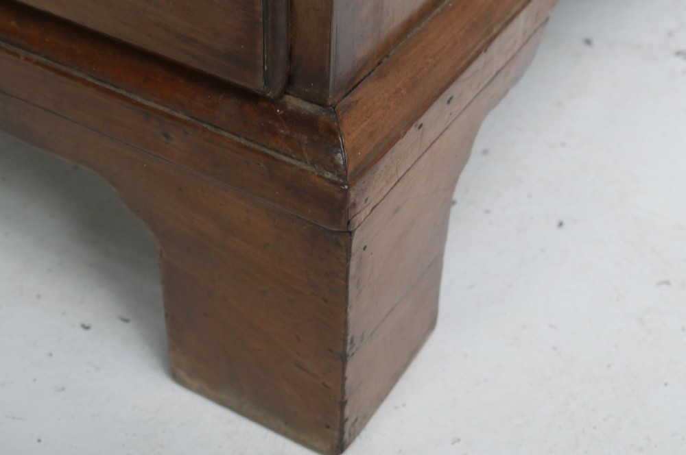 A tall Georgian mahogany bureau bookcase featuring a swan-neck pediment, glazed upper doors, a slant-front writing slope, four long drawers, and bracket feet. View VI