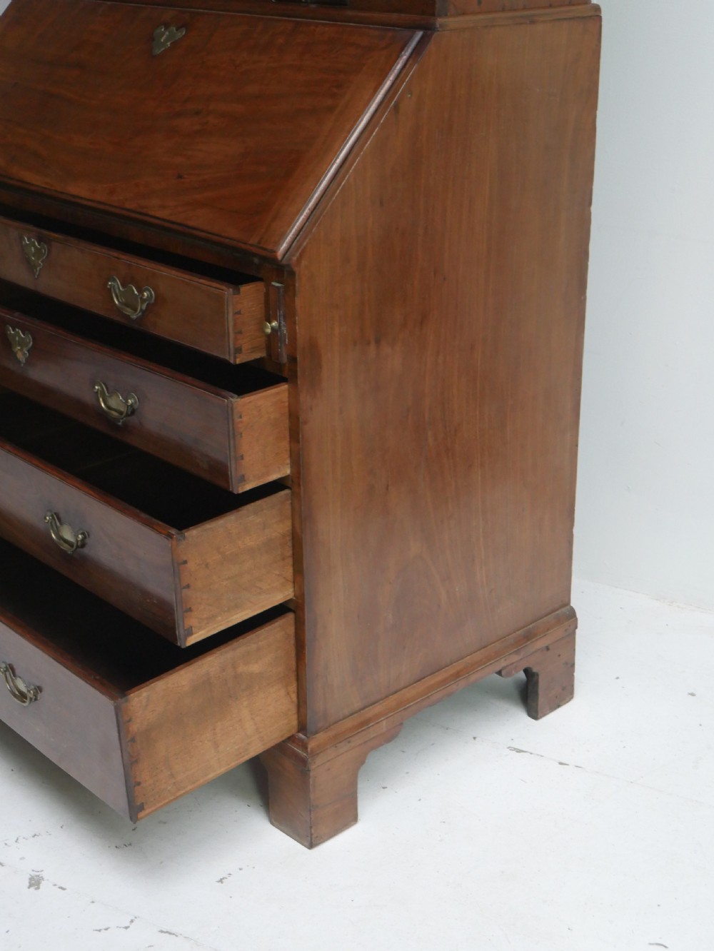 A tall Georgian mahogany bureau bookcase featuring a swan-neck pediment, glazed upper doors, a slant-front writing slope, four long drawers, and bracket feet. View XIII