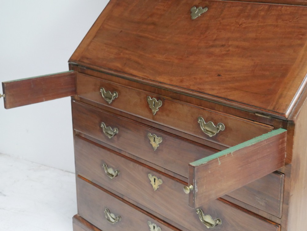 A tall Georgian mahogany bureau bookcase featuring a swan-neck pediment, glazed upper doors, a slant-front writing slope, four long drawers, and bracket feet. View XV