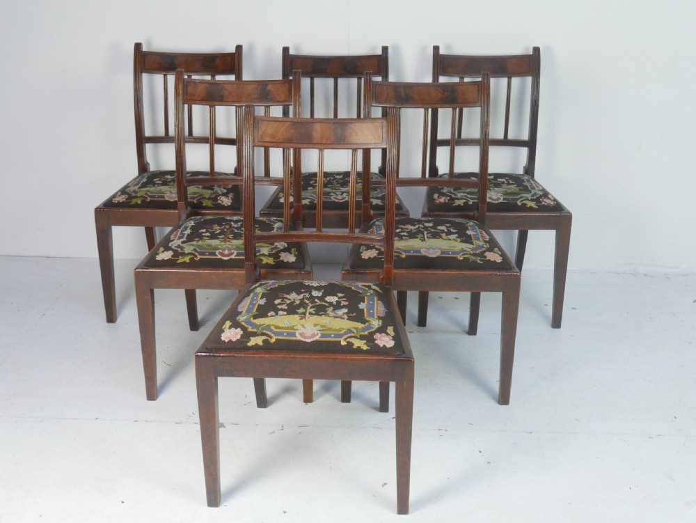 A set of six antique Georgian mahogany dining chairs with reeded vertical bar backs and embroidered needlepoint drop-in seats.