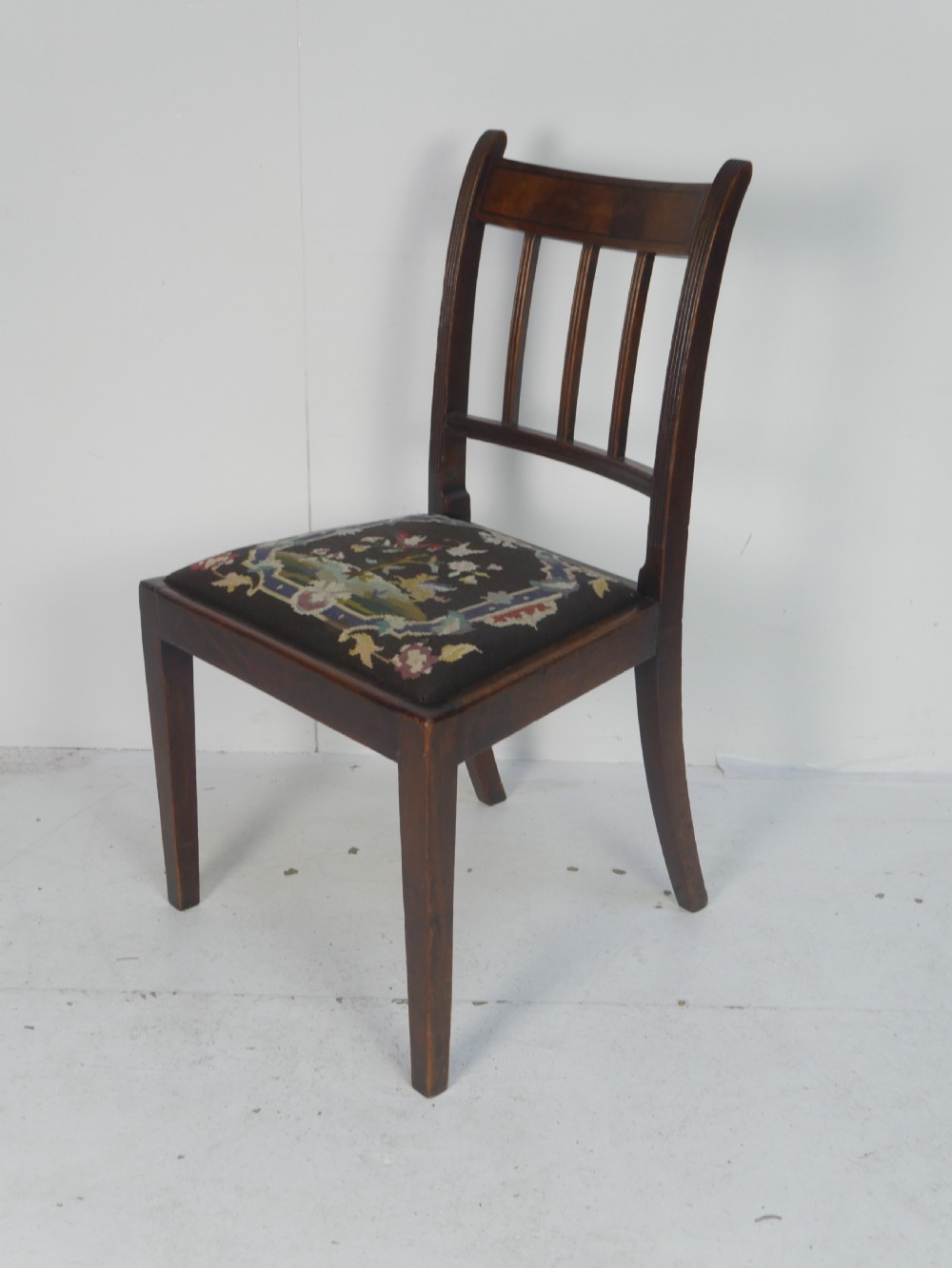 A set of six antique Georgian mahogany dining chairs with reeded vertical bar backs and embroidered needlepoint drop-in seats. View II