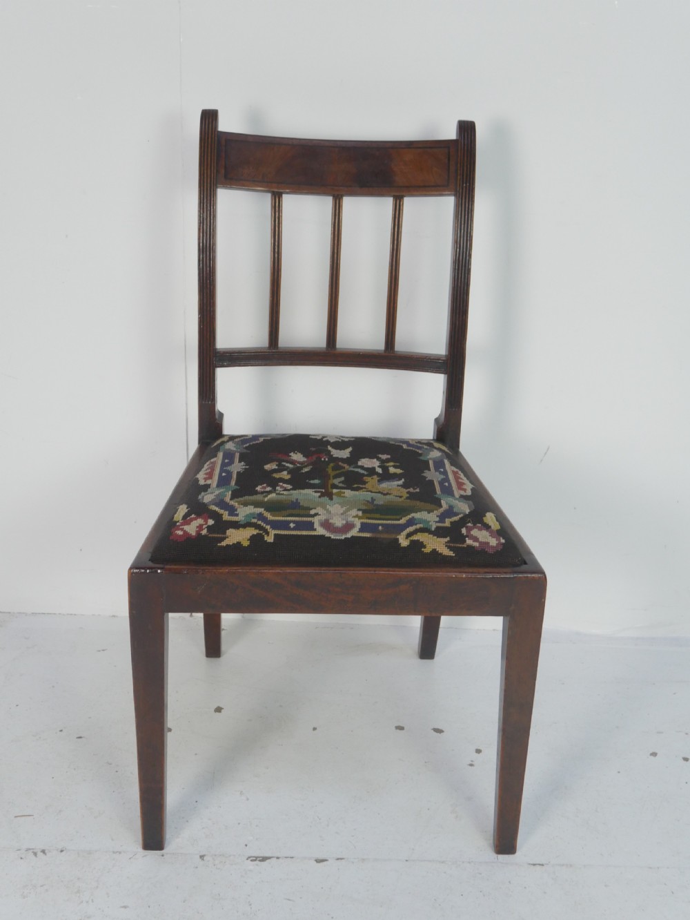 A set of six antique Georgian mahogany dining chairs with reeded vertical bar backs and embroidered needlepoint drop-in seats. View XV