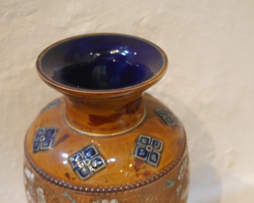 A pair of antique Royal Doulton stoneware vases featuring caramel brown glazing, white floral decorations, and blue foliate accents around the base. View V